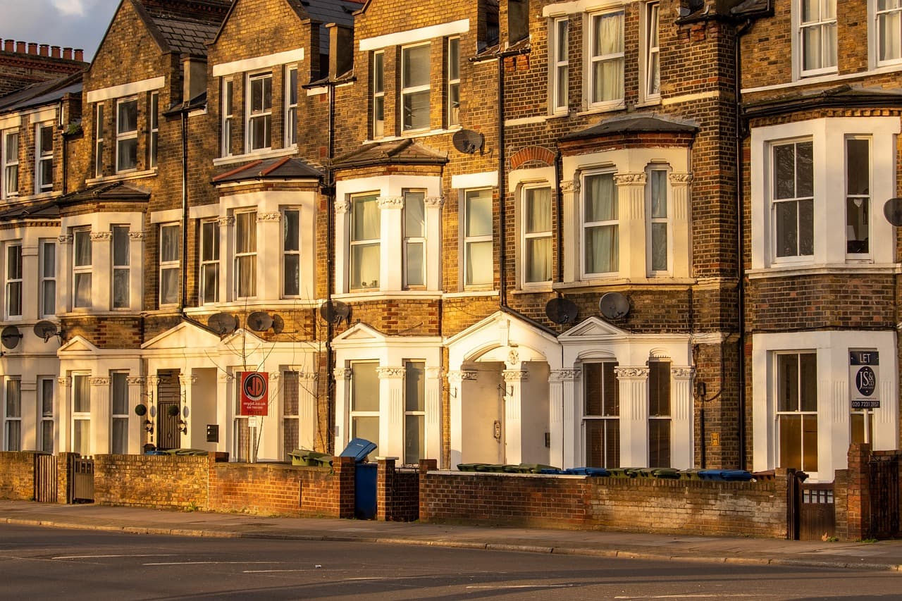 A row of Victorian bay-fronted terraced houses on a quiet British street in evening sun